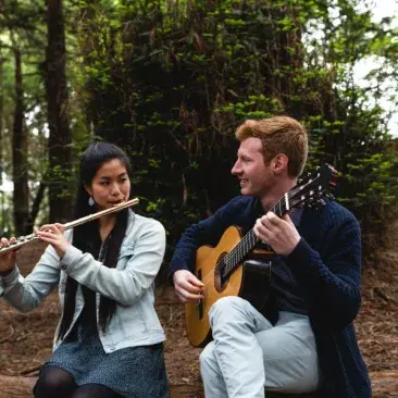 a flutist and guitarist outside playing together