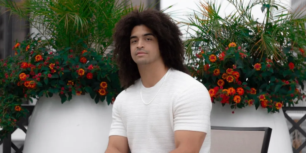 Xavier Muzik sits in front of plants