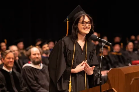 alex kelley speaks at the lectern 