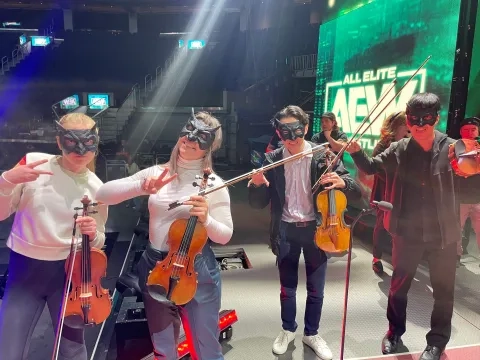 students wearing masks pose holding their instruments at chase center