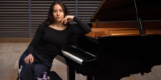 Raquel Fisk at the piano with a set of weights on the bench as well