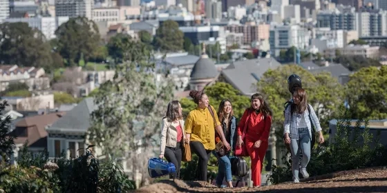 sfcm students walk through a park with their instrument cases