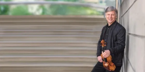 Violinist, Simon James against a wall with his violin